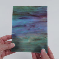 Video of the Azores Marbled Iridised glass plate in iridised translucent blue, 15x19cm, held up and tilted to show its pattern and transparency
